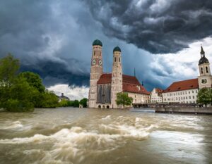 Sturmwolken über Münchner Frauenkirche und heranschäumendes Hochwasser - mit KI generiert