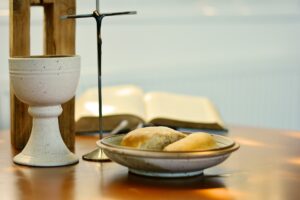 Tisch mit Bibel, Kreuz, Kelch und Brot für Abendmahl